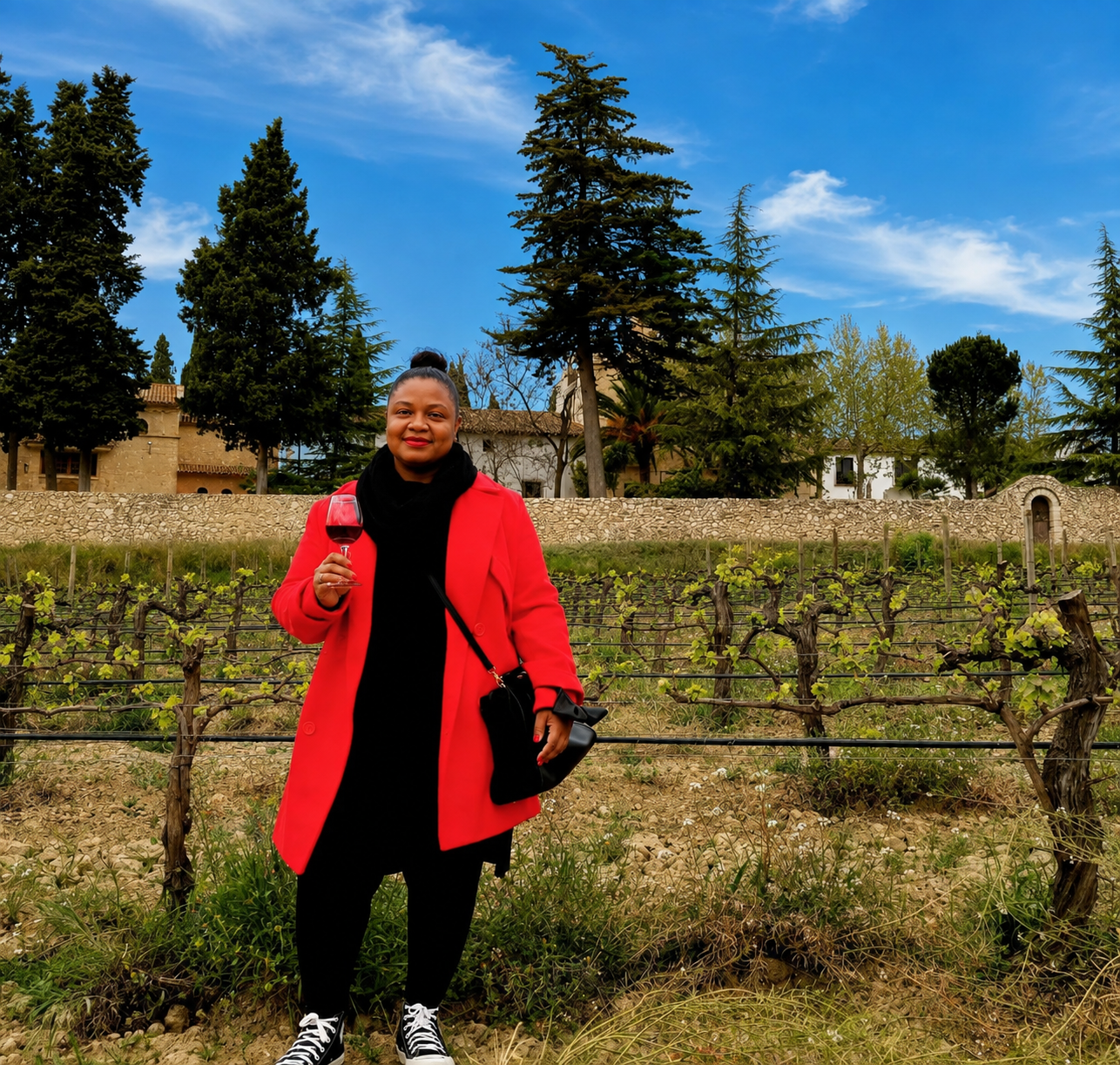 Vinlore founder in a red coat holding a glass of red wine in a vineyard in southern Spain