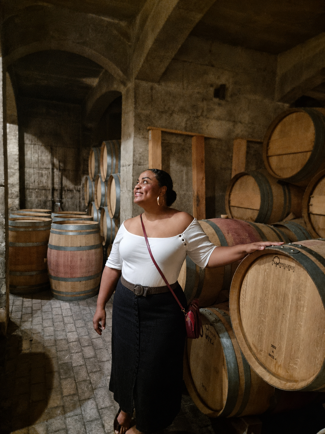 Vinlore founder holding a glass of red wine in a candlelit stone wine cellar
