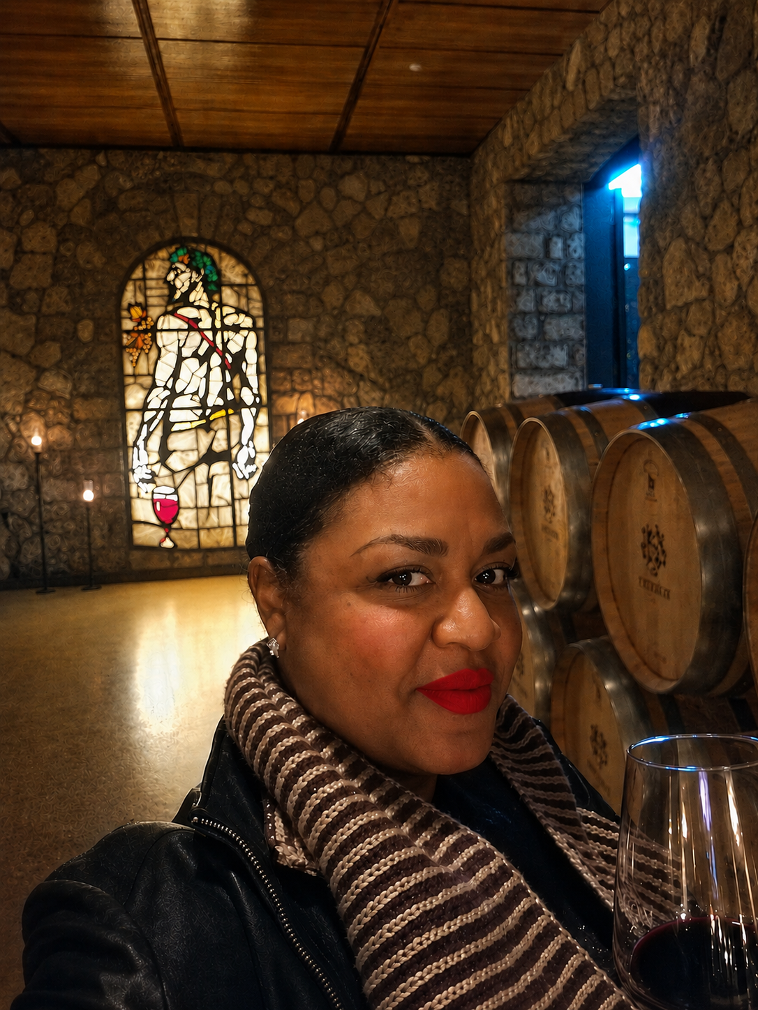 Vinlore founder wearing a striped knit scarf and holding a glass of red wine in a stone cellar
